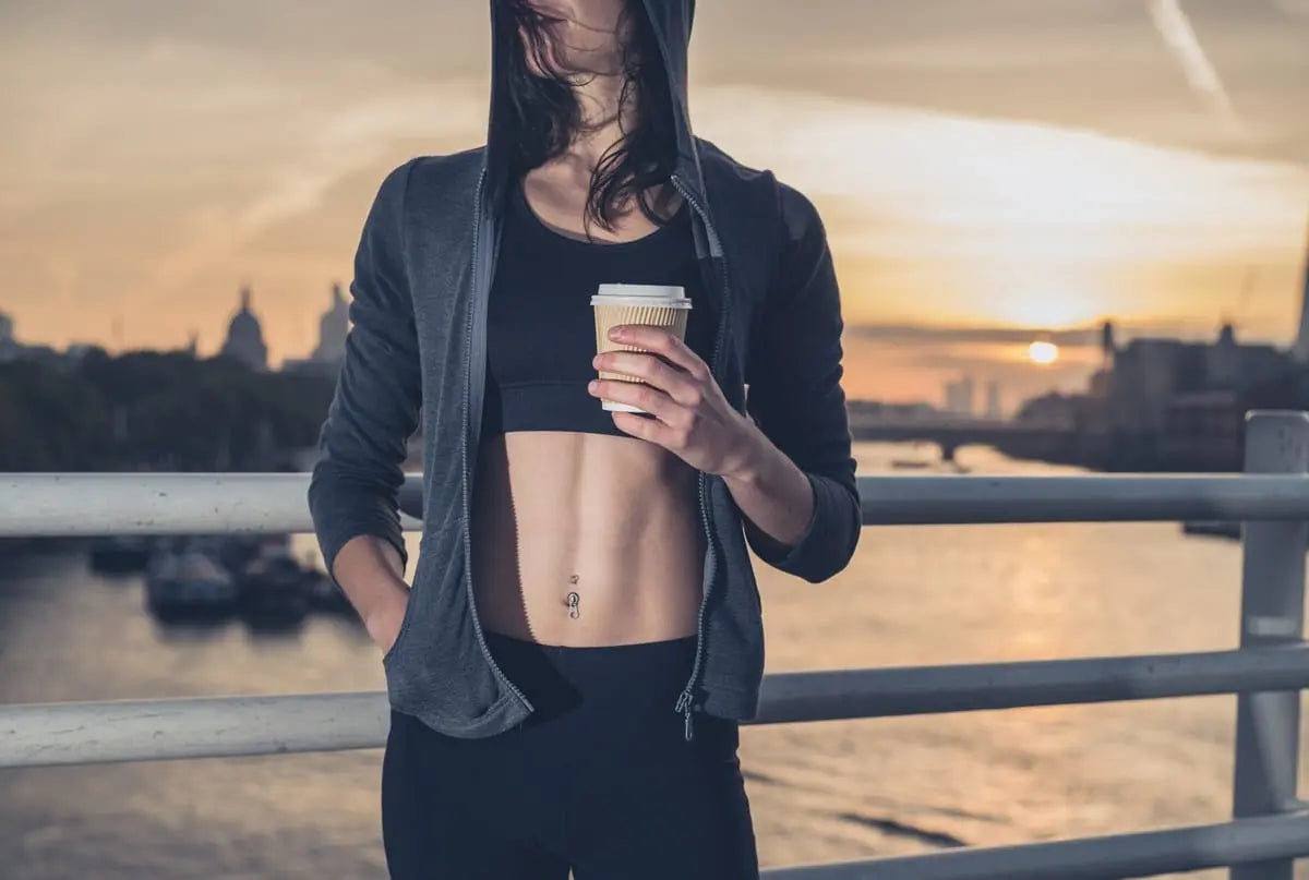 Woman holding coffee on pier at sunset