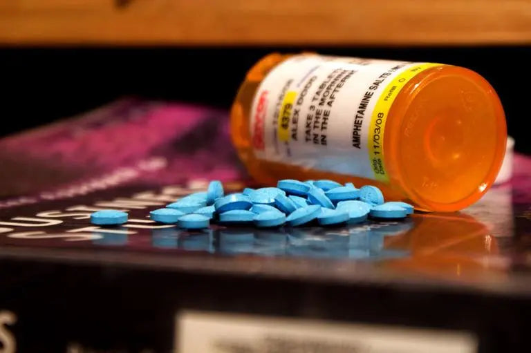 Pill bottle and pile of blue pills