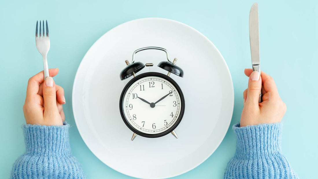 clock on dinner plate with person holding fork and knife