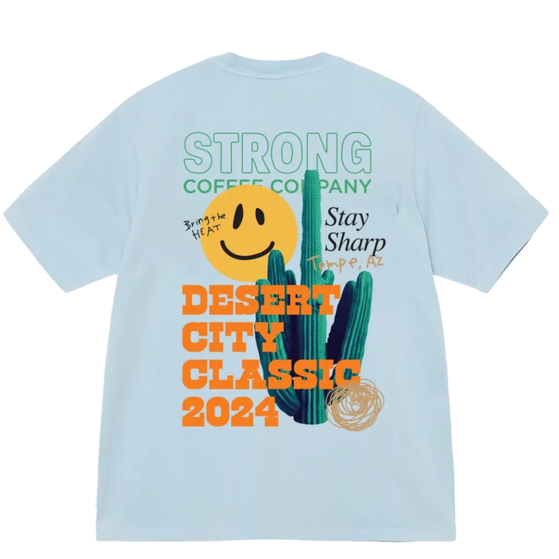A light blue t-shirt with text and graphics related to the Desert City Classic competition, including a smiley face and cactus design.
